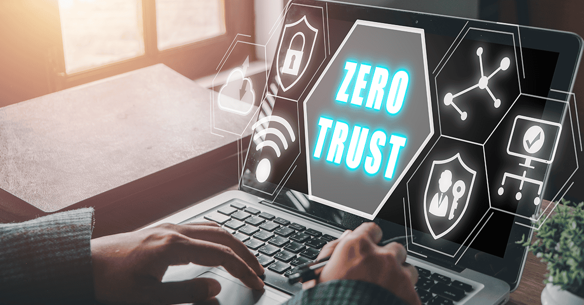 a cropped view of hands typing on a laptop with the phrase “Zero Trust” surrounded by different icons